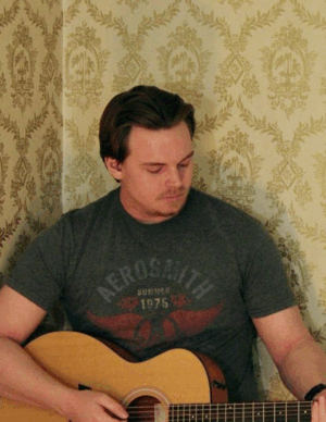 Nate Pearson holding a guitar with yellow damask background